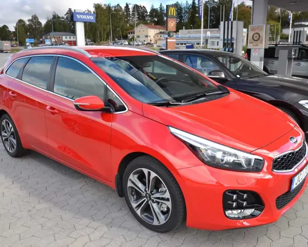 Röd Kia Ceed kombi parkerad vid en bensinstation. En perfekt bil för en kia ceed test.