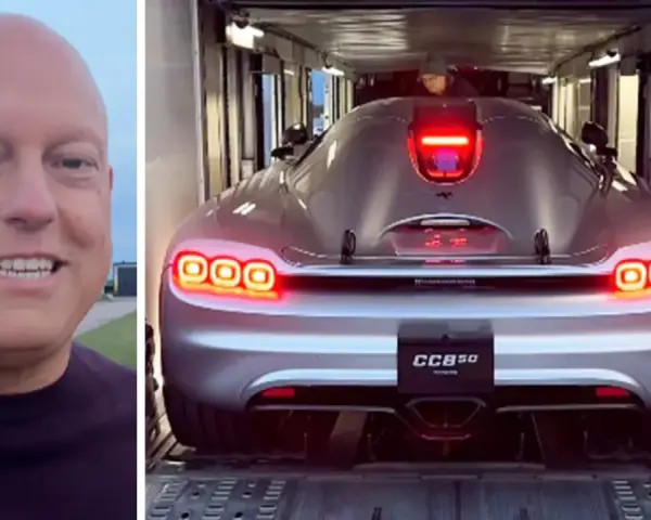En man ler bredvid en silverfärgad Koenigsegg CC850 som lastas in i en trailer.