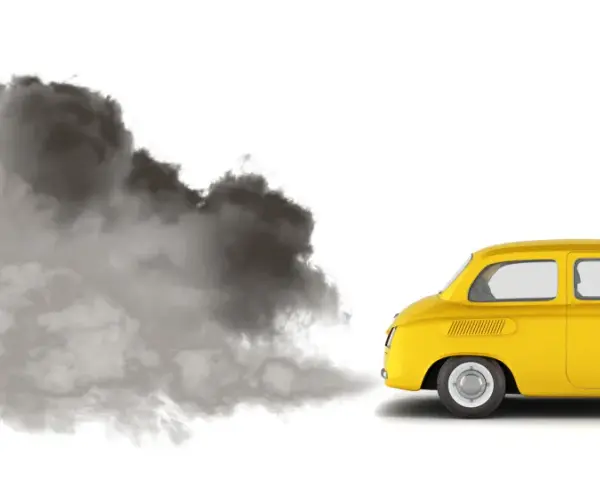 En gul retrobil släpper ut en stor rökpuff. Det luktar avgaser i bilen, en tydlig miljöbild.