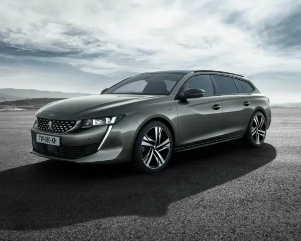 Grå Peugeot 508 SW står parkerad på en asfalterad yta med berg i bakgrunden. En perfekt bil för ett peugeot 508 test.