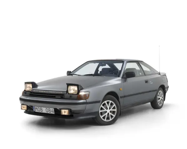 Grå Toyota Celica 1986 med pop-up-strålkastare, redo för en nostalgisk resa.