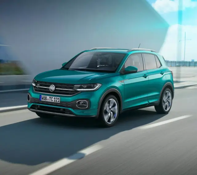 En turkos VW T-Cross kör på en väg. Inga problem med denna bil!