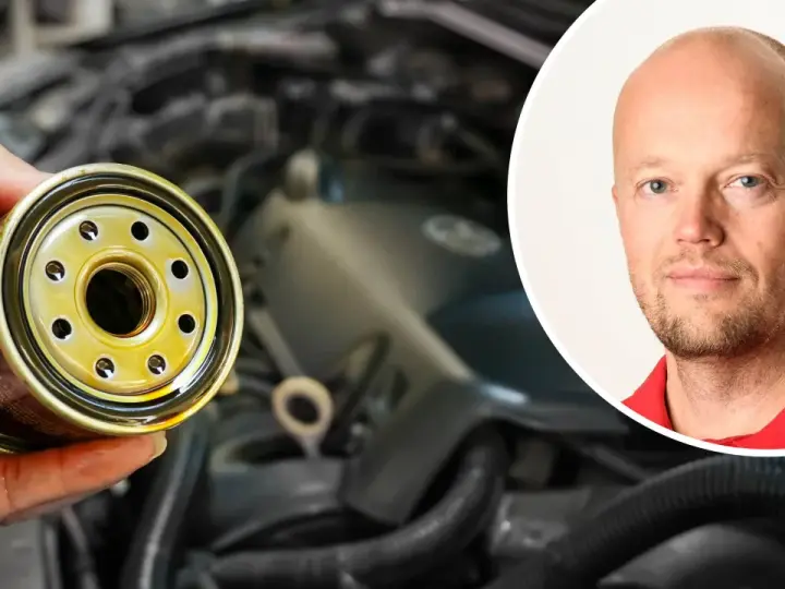 En hand håller ett oljefilter, redo att byta det för att stoppa vobblande ljud från bilen. En man i rött syns i bakgrunden.