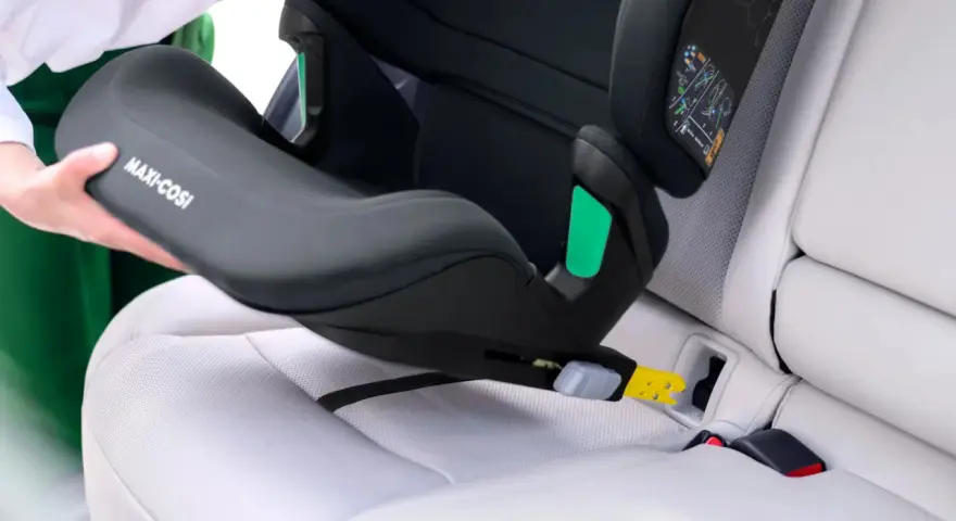 En person monterar en Maxi-Cosi bilbarnstol utan isofix i en bil. Barnstolen placeras på bilsätet och fästs med bilens säkerhetsbälte.