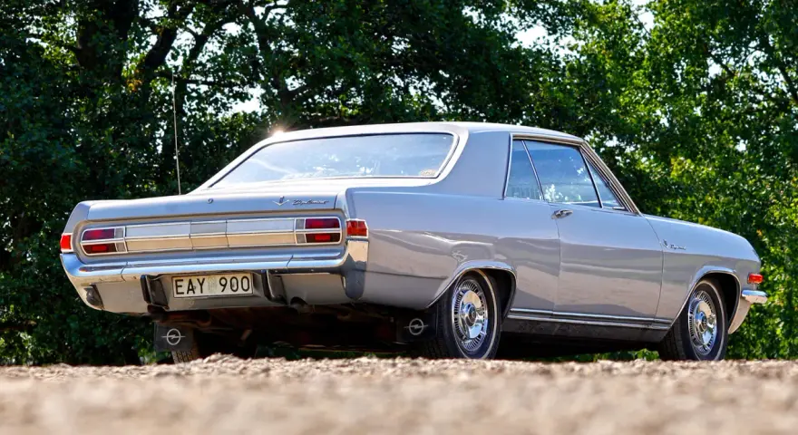 En grå Opel Diplomat coupé står parkerad utomhus.