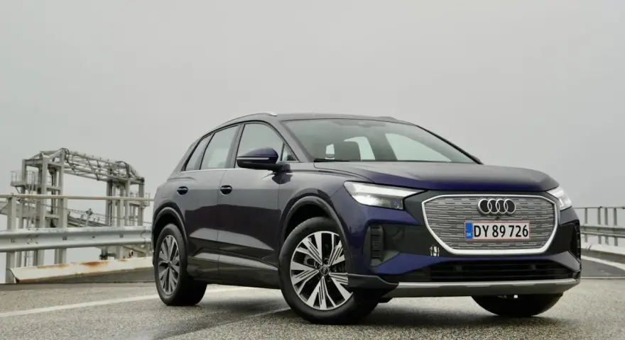 Mörkblå Audi Q4 e-tron på en väg med en bro i bakgrunden. En del av en audi q4 e-tron test.