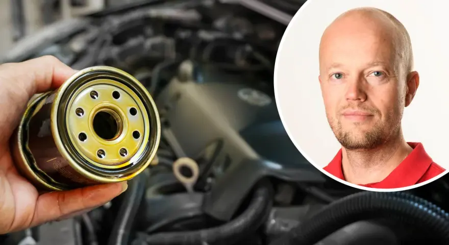 En hand håller ett oljefilter, redo att byta det för att stoppa vobblande ljud från bilen. En man i rött syns i bakgrunden.