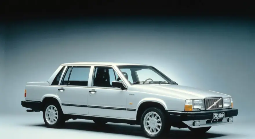 En silverfärgad, gammal Volvo 740 Turbo står uppställd i studio. Bilen har en klassisk design med raka linjer och en distinkt grill.