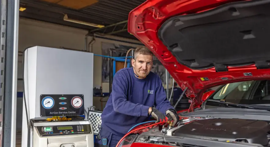 Mekaniker arbetar med bilens AC-system. Lär dig hur fungerar ac i bilen med denna serviceutrustning.