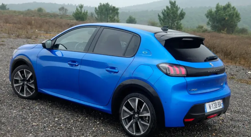 Blå Peugeot e-208 GT på grusväg. En elbil redo för peugeot e-208 test i naturen.