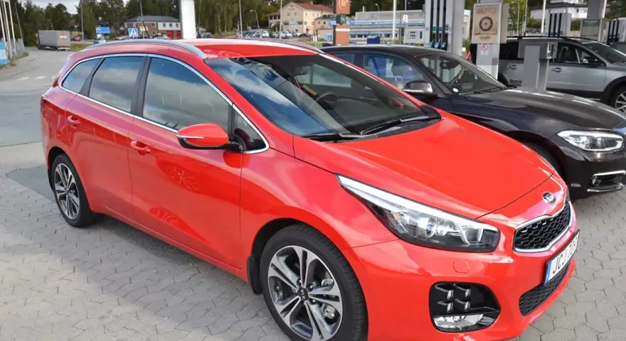 Röd Kia Ceed kombi parkerad vid en bensinstation. En perfekt bil för en kia ceed test.