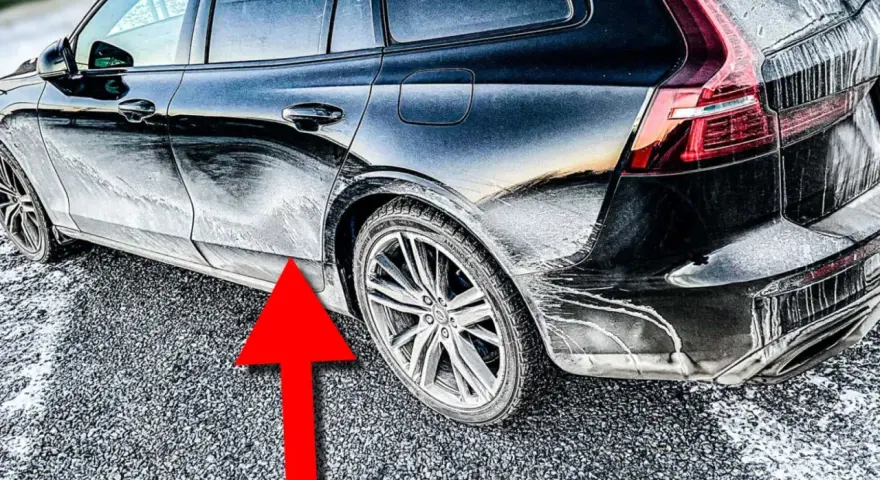 En mörk bil täckt av frost och smuts. En röd pil pekar mot en rostig bil.