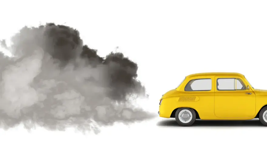 En gul retrobil släpper ut en stor rökpuff. Det luktar avgaser i bilen, en tydlig miljöbild.