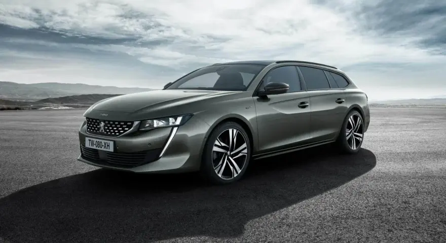 Grå Peugeot 508 SW står parkerad på en asfalterad yta med berg i bakgrunden. En perfekt bil för ett peugeot 508 test.