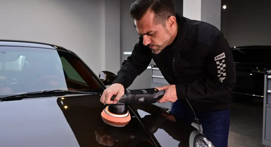 Man använder polermaskin för att polera bilen till perfektion.