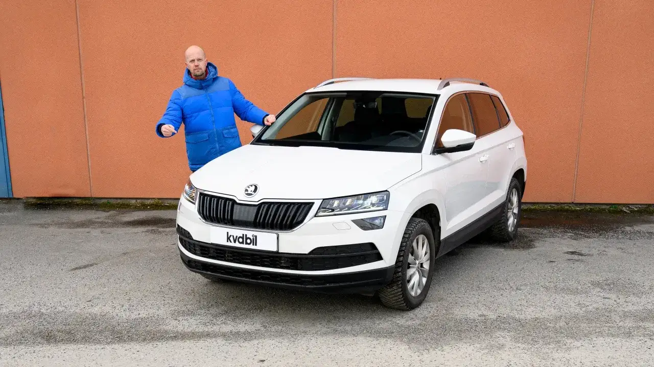 Man pekar p&aring; en vit Skoda Karoq, verkar ha ett problem med bilen.