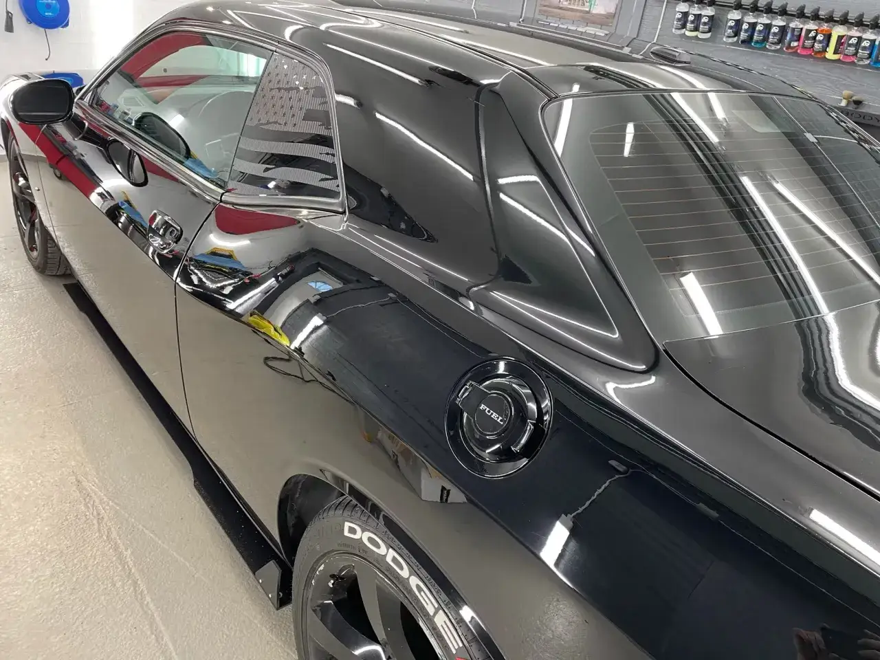 Svart Dodge Challenger med spegelblank lack efter att ha f&aring;tt polera bilen. Amerikansk flagga syns i bakrutan.