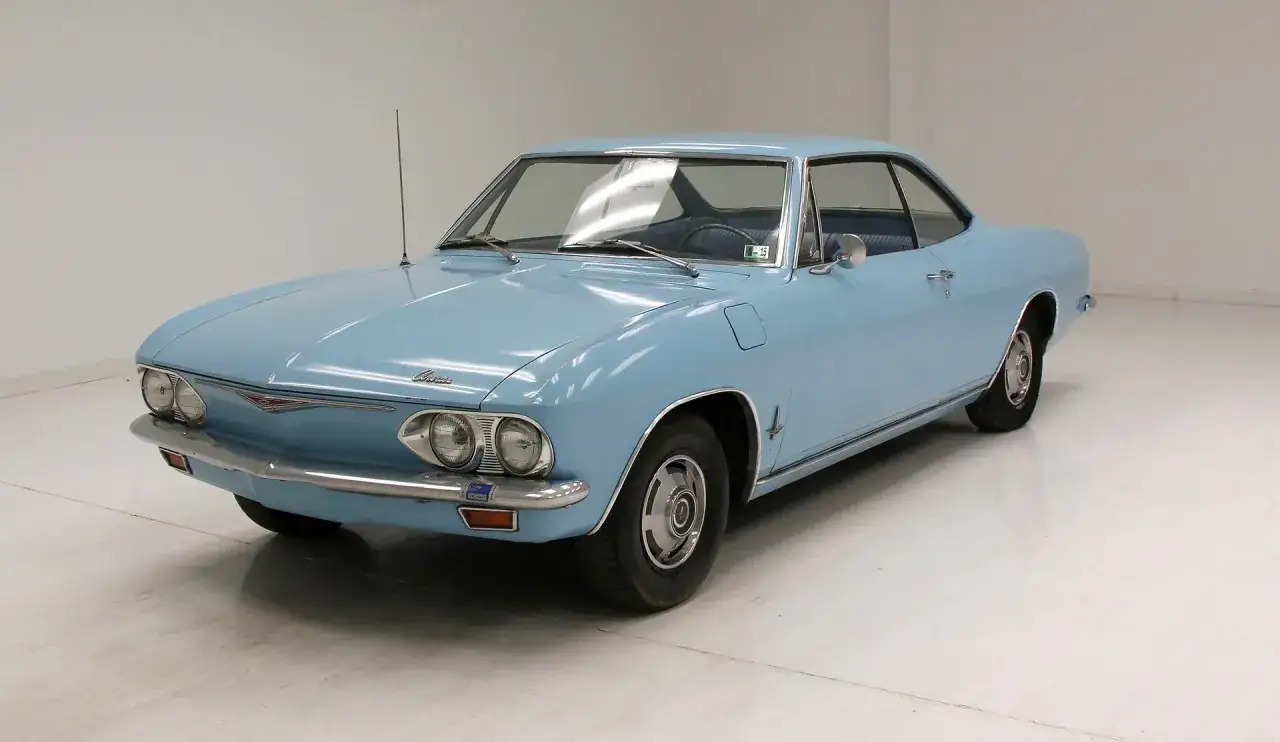Ljusbl&aring; Chevrolet Corvair coup&eacute; med kromdetaljer och antenn. En klassisk amerikansk bil fr&aring;n 60-talet.