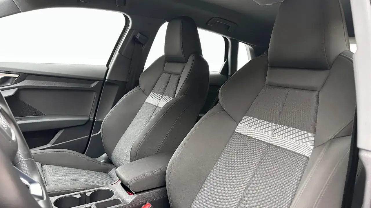 Interiörbild på en Audi A3 med fokus på framsätena. Grå tygsäten med en dekorativ rand. Kanske en titt på audi a3 vanliga fel?