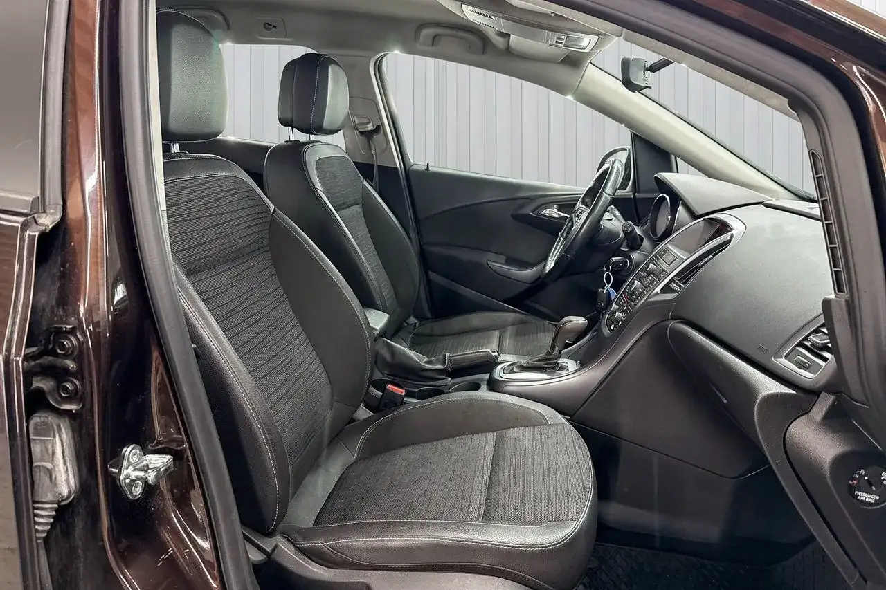 Interi&ouml;rbild p&aring; en m&ouml;rkbrun Opel Astra. Framstolarna &auml;r kl&auml;dda i tyg och l&auml;der. Ratt, instrumentpanel och v&auml;xelspak syns. En bra Opel Astra begagnad test.