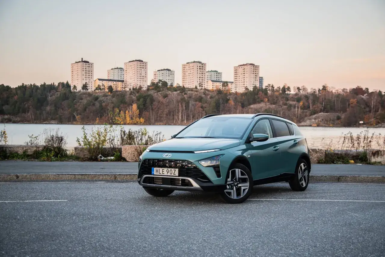Gr&ouml;n Hyundai Bayon parkerad vid en sj&ouml; med stadssiluett i bakgrunden. En perfekt bil f&ouml;r en svensk testk&ouml;rning.