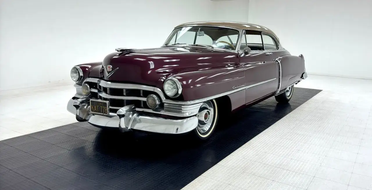 En gl&auml;nsande vinr&ouml;d Cadillac fr&aring;n 50-talet med kromdetaljer och en ljusbrun tak. En tidl&ouml;s klassiker.