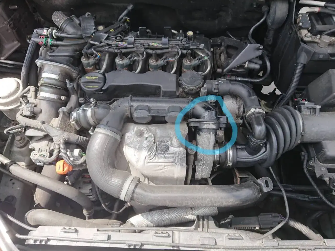 Motorutrymme med fokus p&aring; turbon och insugsr&ouml;ret. En bl&aring; cirkel markerar en del av systemet, m&ouml;jligen relaterat till sotfilter fullt v70.