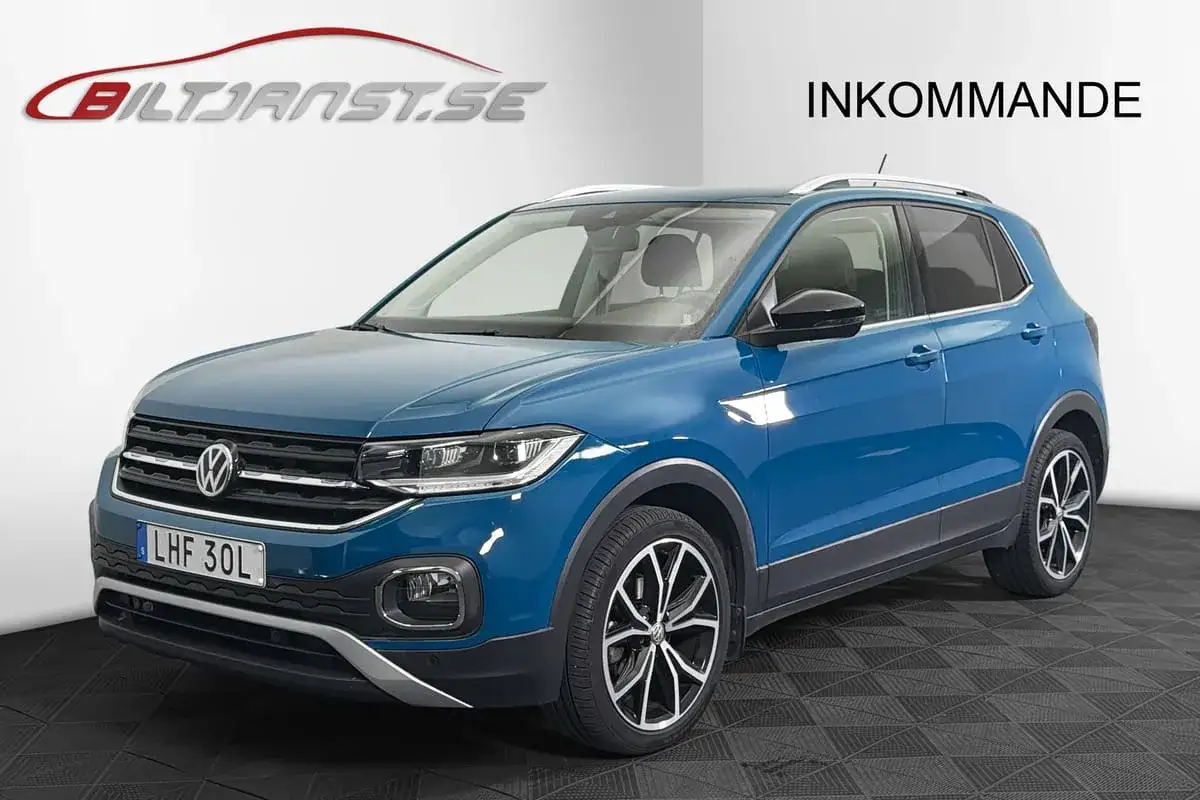 Blå Volkswagen T-Cross, en kompakt SUV, står redo för leverans. Denna t-cross problemfritt tar dig dit du vill.