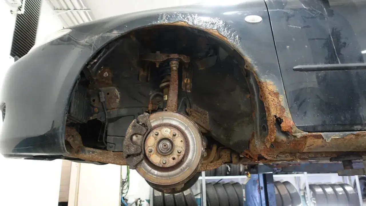 Mazda 6 problem: kraftig rostskada på skärmkant och tröskel. Bromsskiva och hjulupphängning syns också.