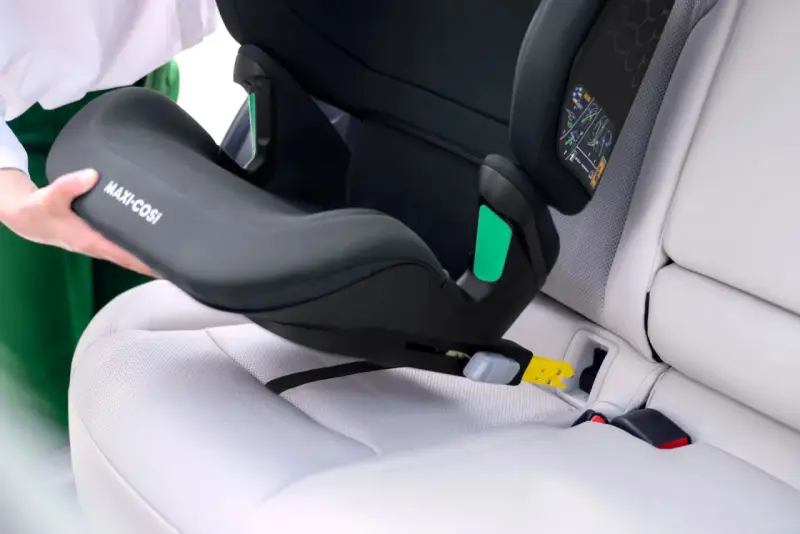 En person monterar en Maxi-Cosi bilbarnstol utan isofix i en bil. Barnstolen placeras på bilsätet och fästs med bilens säkerhetsbälte.